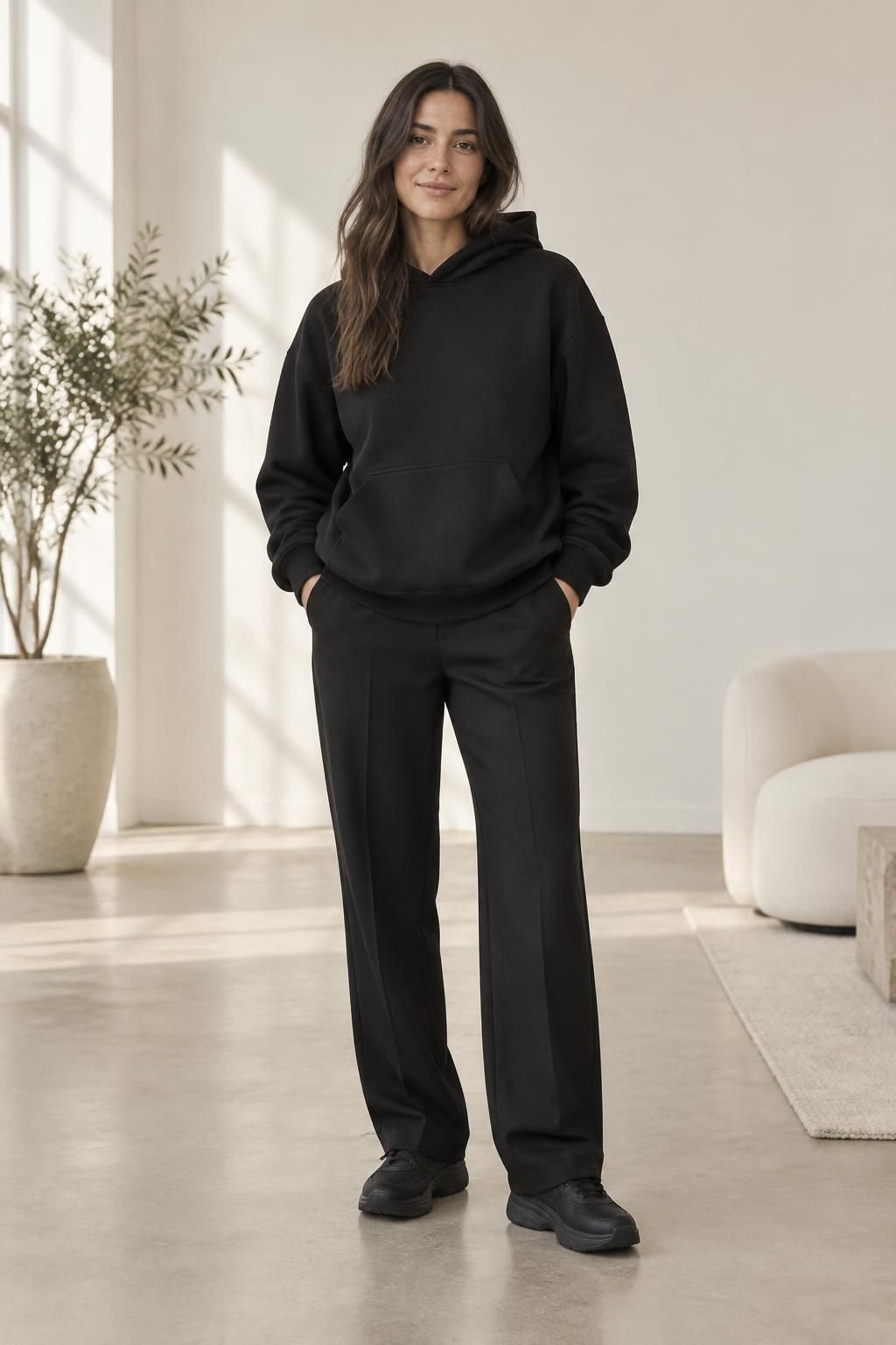All-black outfit with an oversized hoodie, straight-leg trousers, and black sneakers.