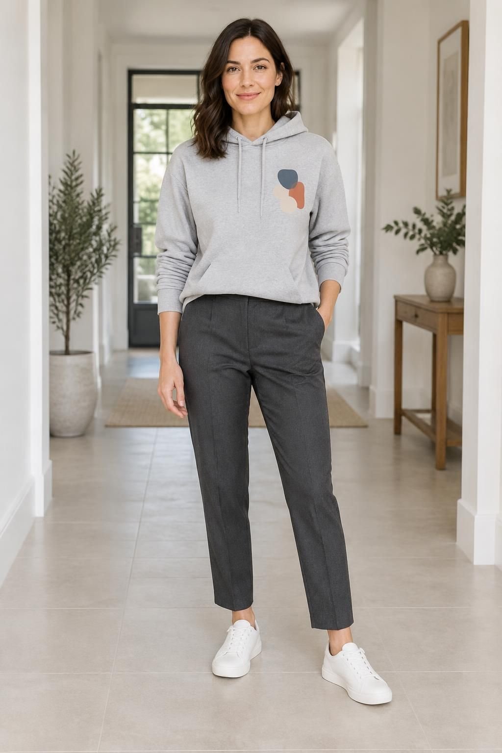 Graphic hoodie with charcoal ankle-length tailored trousers and clean white sneakers.